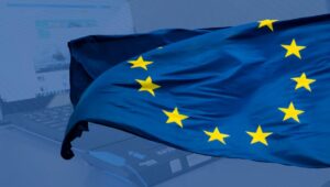 Europäische Flagge weht vor einem Laptop mit Pizza im Vordergrund.